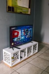 a tv sitting on a white entertainment center at Delightful 1,5 Bedroom Flat in Germiston with WI-FI in Germiston