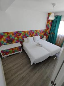 a bedroom with two white beds and a colorful wall at rural relax in Villar del Arzobispo