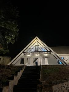 VaduvanchalCloud9 Glamping - Private Aframe Villa的白色的建筑,晚上有楼梯通往