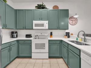 Una cocina verde con electrodomésticos blancos y gabinetes verdes. en 3 Bedroom Condo In Fabulous Resort Near Disney World, en Kissimmee