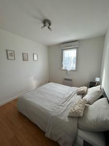 a white bedroom with a bed and a window at Appartement T3 proche circuit du Mans in Allonnes