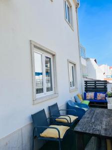 a patio with blue chairs and a table and a window at 70's Hostel in Ericeira +20 photos