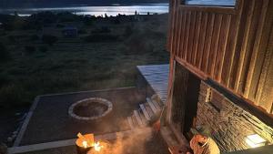 a man standing outside of a building with a fire pit at Cabañas Lodge Puerta Roja in Los Helechos