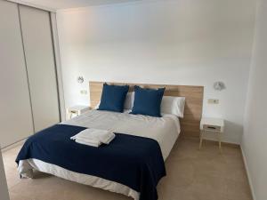 a bedroom with a large bed with blue pillows at Apartamentos Telleira in Nigrán +16 photos