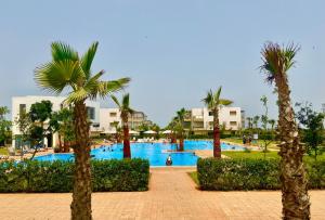 a resort with a swimming pool with palm trees at Sidi rahal Blue beach in Sidi Rahal