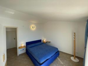 ein Schlafzimmer mit einem blauen Bett in einem weißen Zimmer in der Unterkunft The Seaside Serenity Terrace in Giardini-Naxos