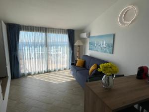 ein Wohnzimmer mit einem blauen Sofa und einem Tisch in der Unterkunft The Seaside Serenity Terrace in Giardini-Naxos