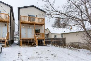 a house with a deck in the snow at 3Bedrooms Apartment Near YWG Airport in Winnipeg