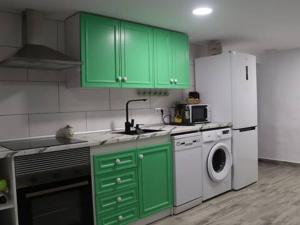 a kitchen with green cabinets and a white refrigerator at Casa Nostra Alcanar in Alcanar