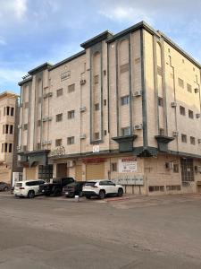 een groot gebouw met auto's geparkeerd op een parkeerplaats bij شقق مفروشة 22 in Al Madinah