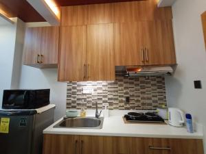 a kitchen with a sink and a stove and wooden cabinets at B&M Rental- Antara in San Isidro +9 photos