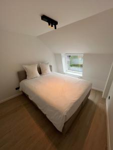 a bedroom with a large white bed with a window at Maison Ter Wallen in Izegem