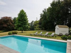 a swimming pool with two chairs and a shed at Maison Ter Wallen in Izegem