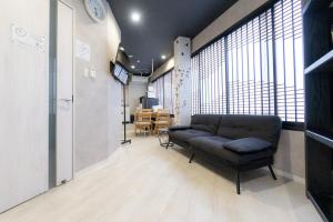 大阪市にある4F Guest House NETOMARI 西九条駅から徒歩2分のソファと大きな窓のあるリビングルーム