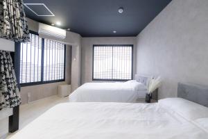 大阪市にある4F Guest House NETOMARI 西九条駅から徒歩2分のベッドルーム1室(白いベッド2台、窓2つ付)