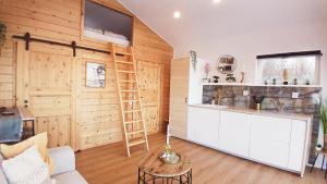 sala de estar con paredes de madera y cocina con escalera. en Loft-Sleeps5-Parking-Spa-LakeViews-PetFriendly, en Finnerödja
