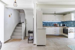 a kitchen with white cabinets and a staircase at The Lovely Gem in Skopelos Town