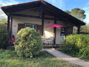 ein kleines Haus mit einem Tisch und einem Sonnenschirm in der Unterkunft Chez Marielle in Parentis-en-Born