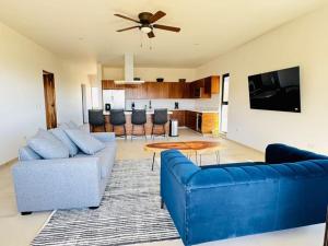 a living room with two blue couches and a kitchen at Los Cerritos Oceanview at The Point,8 in San Carlos