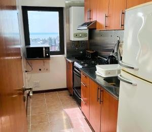 a kitchen with wooden cabinets and a white refrigerator at Excelente departamento, a metros del Shopping Paso del Paraná, vista al río Paraná - silencio - ideal para descansar - barrio residencial - Cámaras de seguridad 24hs - unidad Monitoreada in Paraná