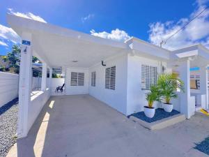 a white house with two potted plants in front of it at Casa Soluna in Arecibo