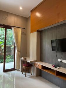 un salon avec une télévision sur un mur dans l'établissement Adi Jaya Cottages Ubud Suites by EPS - CHSE Certified, à Ubud
