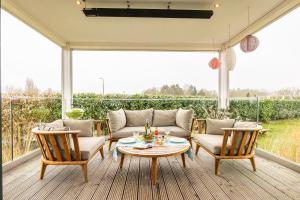 a porch with a couch and chairs and a table at Maasparcje ecoLodge K2 Roermond in Roermond
