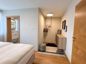 ゼーキルヒェン・アム・ヴァラーゼーにある"ONE" - Premium Apartments Seekirchen - Dein Rückzugsort mit exklusivem Flair und privater Terrasseのベッドルーム1室(ベッド1台付)、ドア(スツール付)