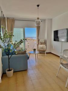 un salon avec un canapé bleu et une table dans l'établissement Vistas al mar primera linea playa Valdelagrana, à El Puerto de Santa María