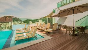 uma piscina com cadeiras, uma mesa e um guarda-sol em Américas Copacabana Hotel no Rio de Janeiro