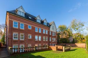 a large brick building with a fence in front of it at Modern 2-Bedroom Apartments with Free Parking in Leamington Spa in Leamington Spa