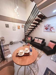a living room with a table and a spiral staircase at The Loft 2 in Cabanatuan +21 photos