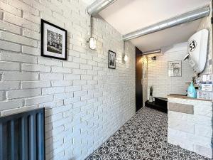 a hallway with a white brick wall and a tile floor at Evasion Verdoyante Vue sur jardin avec balcon et parking in Montigny-le-Bretonneux