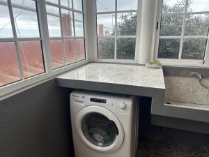 een wasmachine in een wasruimte met ramen bij Casa Mary Bela's in Ponta do Sol