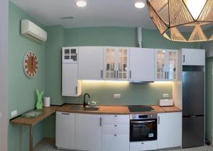 a kitchen with white cabinets and a black refrigerator at Delicias Beach in Málaga
