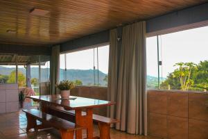 a dining room with a table and large windows at Casa de temporada - Tatuhouse in José Boiteux