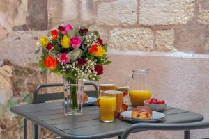 a table with a vase of flowers and orange juice at La Cour du Cygne - By PrestiPlace in Tours