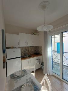 a kitchen with a table and a white refrigerator at Kea's Living Yard II in Korissia