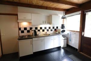 a kitchen with white cabinets and black and white tiles at Trésors de Lilain in Cheylade