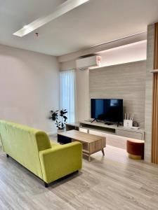 a living room with a green couch and a tv at Queensland Suites at Aru Suites, Kota Kinabalu 2 Bedroom Family Suite in Kota Kinabalu