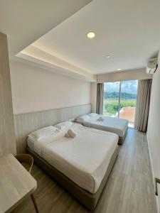 two beds in a hotel room with a window at Queensland Suites at Aru Suites, Kota Kinabalu 2 Bedroom Family Suite in Kota Kinabalu