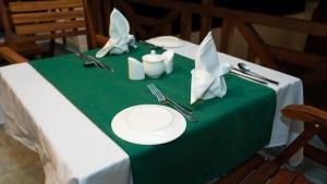 a table with a green table cloth with plates and utensils at Alfa Boutique Hotel in Kiwengwa +18 photos