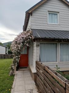 a house with a red door with a flowering tree at La casa de Gaby in San Martín de los Andes