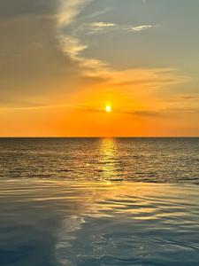 a sunset over the ocean with the sun setting at Bamboo Beach Tsikhisdziri! Enjoy your stay! in Tsikhisdziri