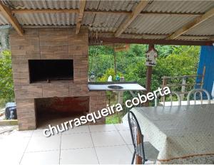 a stone fireplace with a television on a patio at Chácara Azul, chácara privativa com piscina para descanso e lazer in Contenda