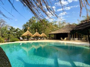 una piscina con sombrillas de paja y un complejo en Maison Fimela, en Fimela