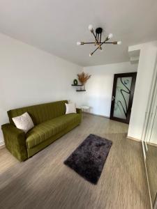- un salon avec un canapé vert et un tapis dans l'établissement Apartament Brazdă, à Craiova