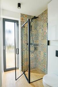 a bathroom with a shower with a tile wall at Domki z Widokiem Klikuszowa jacuzzi in Klikuszowa