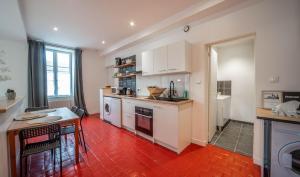 a kitchen with white cabinets and a red floor at Le refuge citadin in Tournus