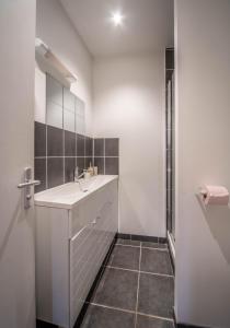a white bathroom with a sink and a shower at Le refuge citadin in Tournus